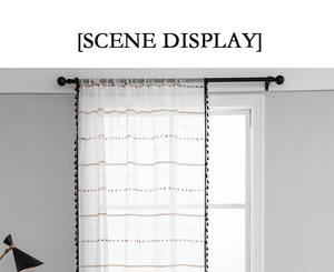 Detail view of white sheer curtain with colorful tufted stripes and black side tassels