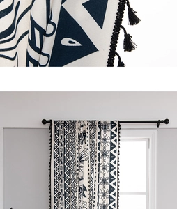 Detail of boho curtain with black floral pattern and tassel trim on beige cotton linen