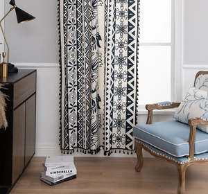 Close-up of bohemian linen curtain with blue floral patterns and black tassel trim