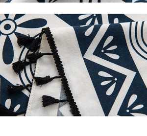 Detailed close-up of blue and white floral pattern linen fabric with black tassels