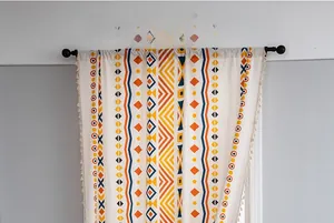 Detail of bohemian geometric print curtain with beige fringes and colorful tassels