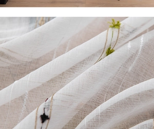 Detailed macro view of white sheer curtain with delicate floral plant embroidery