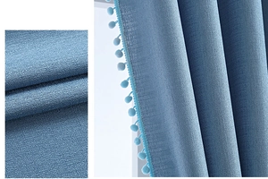 Detail von blauem Leinenvorhangstoff mit dekorativem Bommel-Bortenbesatz am Rand
