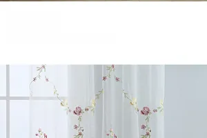 Detailed view of pink and yellow rose floral embroidery on white sheer tulle curtain