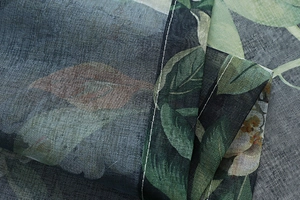 Close-up of the neat white stitching on the hem of a floral cotton linen curtain