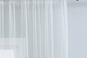 Detail of white sheer curtain with elegant floral embroidery and textured pleats