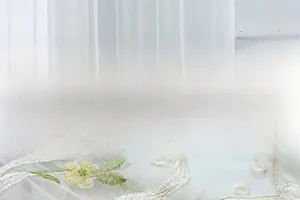 Detail of white sheer curtain with yellow floral embroidery and delicate texture