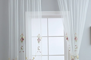 Detailed view of white sheer curtain featuring elegant rose embroidery and floral patterns