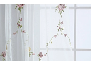Detail of white semi-sheer curtain with elegant pink and yellow floral embroidery