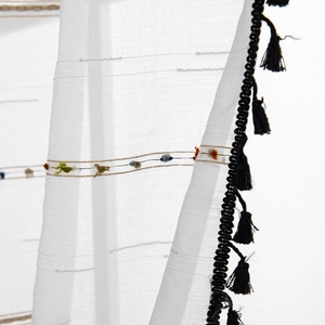 White geometric sheer curtain with black tassels and colorful bohemian embroidery