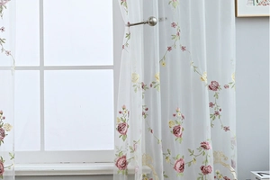 Detail of white semi-sheer curtain with pink rose embroidery and green leaves vines