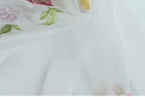 Detail of white mesh curtain featuring delicate floral embroidery and sheer texture