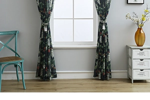 Detail of floral semi-sheer cotton linen curtain with tassel tiebacks in a rustic home setting