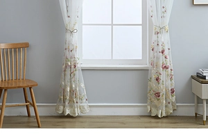 Detail of white tulle curtain with red rose floral embroidery and fringe tiebacks