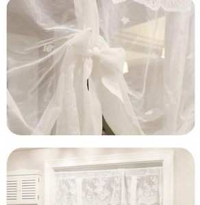 Dettaglio della tenda in pizzo bianco con delicati ricami floreali e nastro decorativo