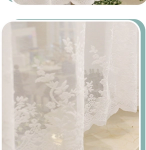 Close-up of white floral lace curtain detail showing delicate embroidery and scallop edges