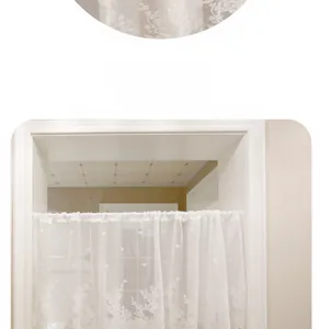 Detailed close-up of white lace curtain with floral embroidery and scalloped edge finish