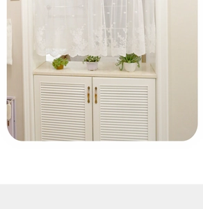 Close-up of white lace curtain with delicate floral embroidery on a cabinet window