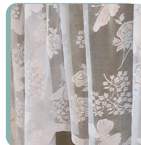 Detail of white lace curtain fabric featuring floral rose and butterfly jacquard patterns