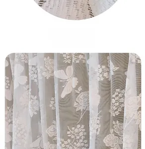 Detail showing white floral lace curtain with butterfly and rose embroidery patterns