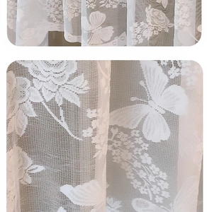 Detailed close-up of white lace curtain featuring delicate butterfly and rose patterns
