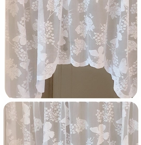 Detailed macro view of white lace curtain fabric featuring rose and butterfly patterns