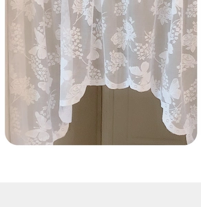 Detail of white lace curtain with floral rose patterns and scalloped decorative bottom edge