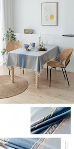 Détail d'une nappe grise imperméable avec pompons blancs et motifs géométriques bleus
