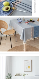 Gros plan sur la nappe nordique gris-bleu avec motifs floraux orange et pompons fins