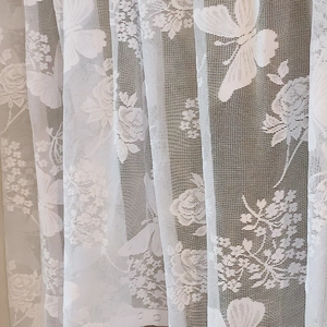 White lace curtain with delicate butterfly and rose floral patterns in sheer mesh fabric
