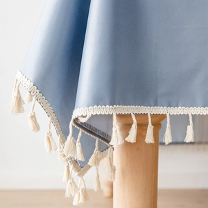 Blaue PVC-Tischdecke wasserdicht mit weißen Quasten auf einer Holztischkante
