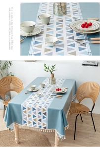 Detail of grey-blue PVC tablecloth featuring geometric patterns and white fringe tassels