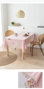 Detail of pink cotton linen tablecloth with light bulb pattern and white fringe edge