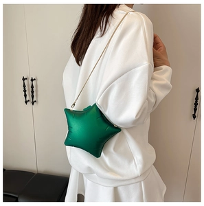 Detail of green star-shaped crossbody bag with gold chain strap worn by a model