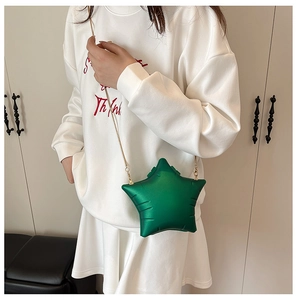Detail of star-shaped green acrylic handbag with gold chain strap on shoulder