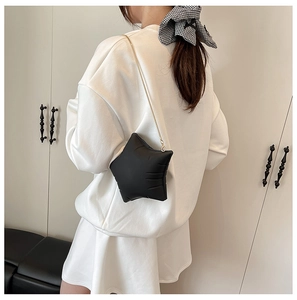 Detail of star-shaped crossbody bag with quilted texture and gold chain strap
