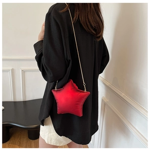 Detail shot of a red star-shaped quilted crossbody bag with a fine gold chain strap