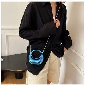 Detalle del mini bolso bandolera azul metálico con asa redonda y cadena dorada
