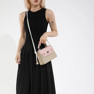 Mini sac bandoulière en paille avec rabat en cuir rose porté par un mannequin chic