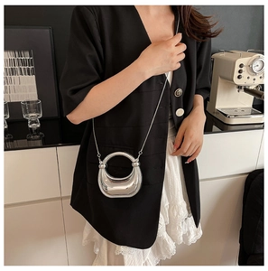 Elegante bolso de mano plateado metalizado con cadena de acrílico en un entorno refinado