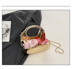 Detail view of mini gold chain bag showing internal capacity for cosmetics and lip gloss