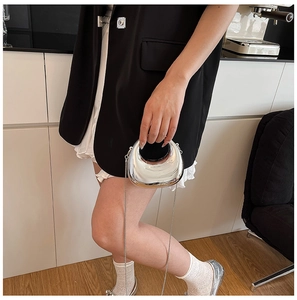 Detail of silver mirror mini chain bag with unique circular cutout handle design