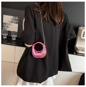 Detalle de bolso rosa metalizado con correa de cadena dorada sobre el hombro