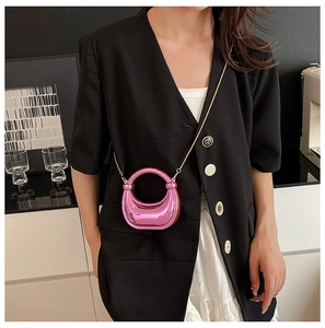 Primer plano de bolso media luna rosa metalizado con cadena dorada sobre un blazer