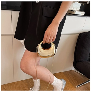 Close-up of golden metallic half-moon mini bag with high-shine finish and chain strap