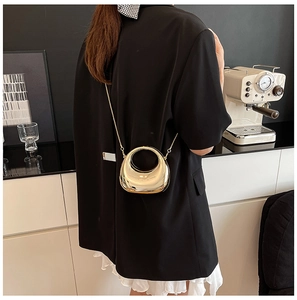 Chic gold crescent mini bag with chain strap and round handle worn by model