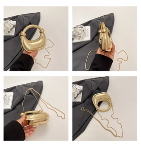 Detalle del bolso de noche dorado en forma de media luna con cadena y diseño de nudo