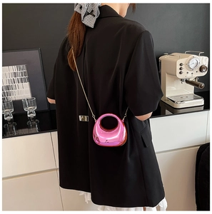 Detail of metallic pink mini bag with golden chain strap worn over a black blazer