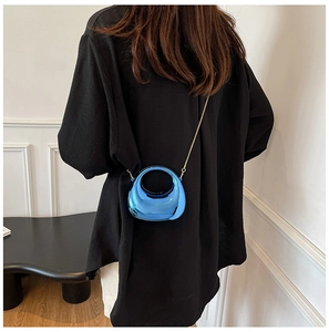 Glossy blue metallic half-moon mini bag with gold chain strap shown on a model