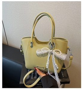 Détail du sac seau vert clair en cuir grainé avec nœud en dentelle et perle